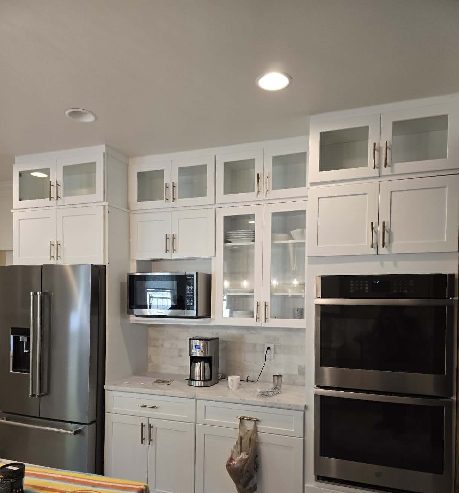 Kitchen wall of cabinetry with built-in double oven and refrigerator